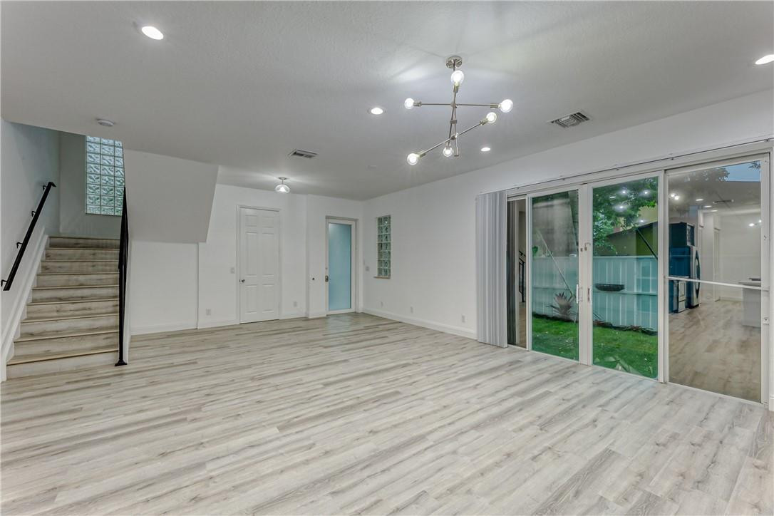Open living area with pale wood flooring, a staircase, and sliding glass doors to the yard.
