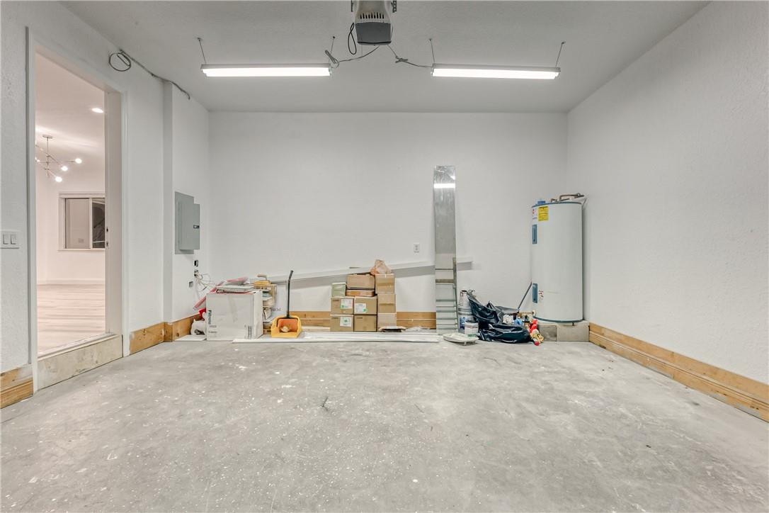 Unfinished garage with a concrete floor, wall-mounted water heater, and stored boxes.