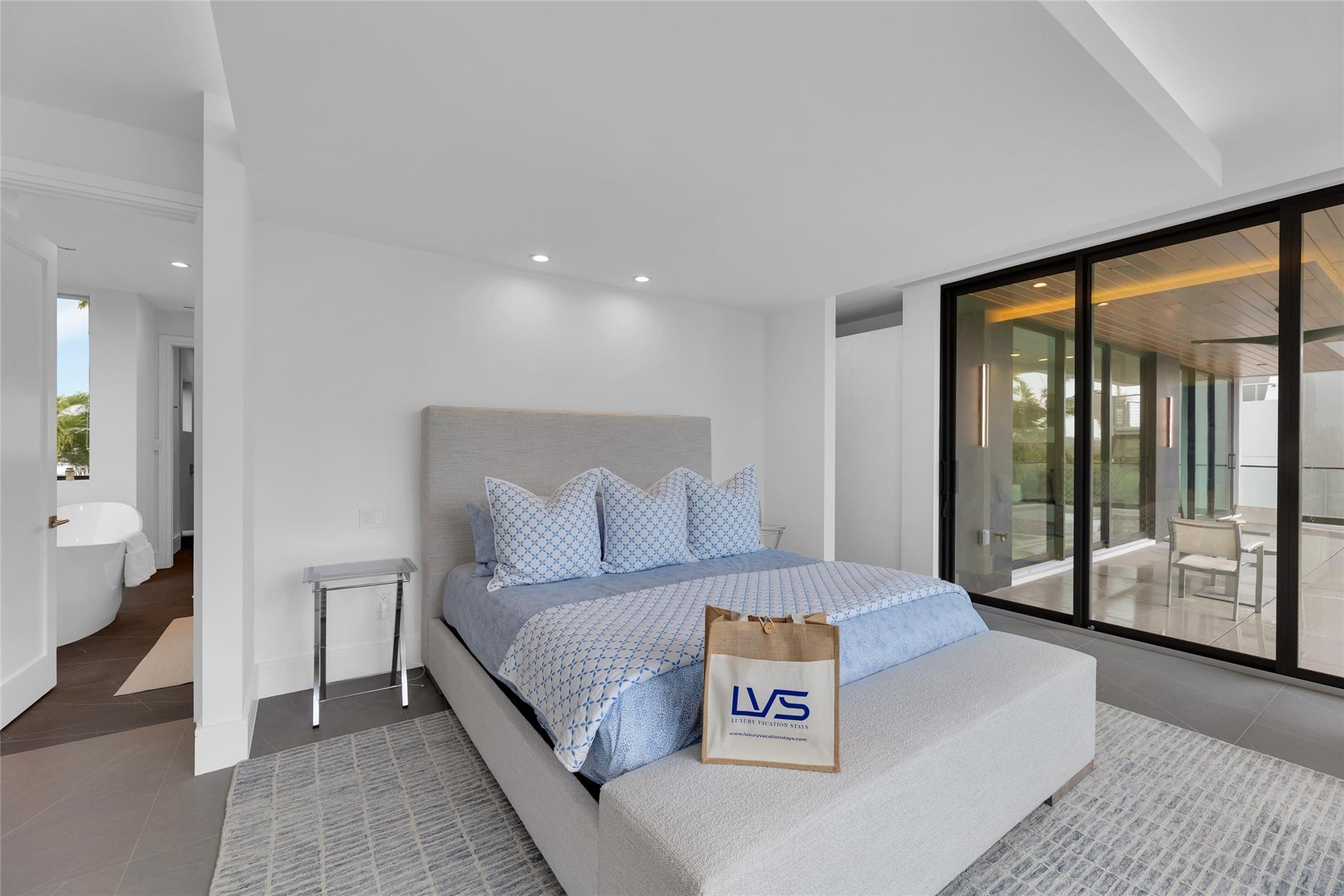 Bedroom with a gray upholstered bed, blue patterned bedding, and sliding glass doors to a covered terrace.