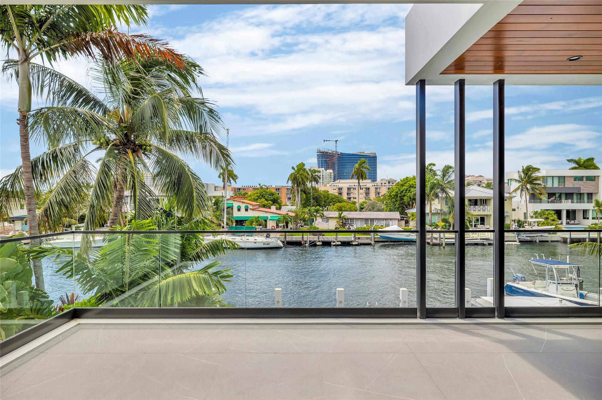 Tiled balcony overlooking a palm-lined canal with docked boats and waterfront homes.