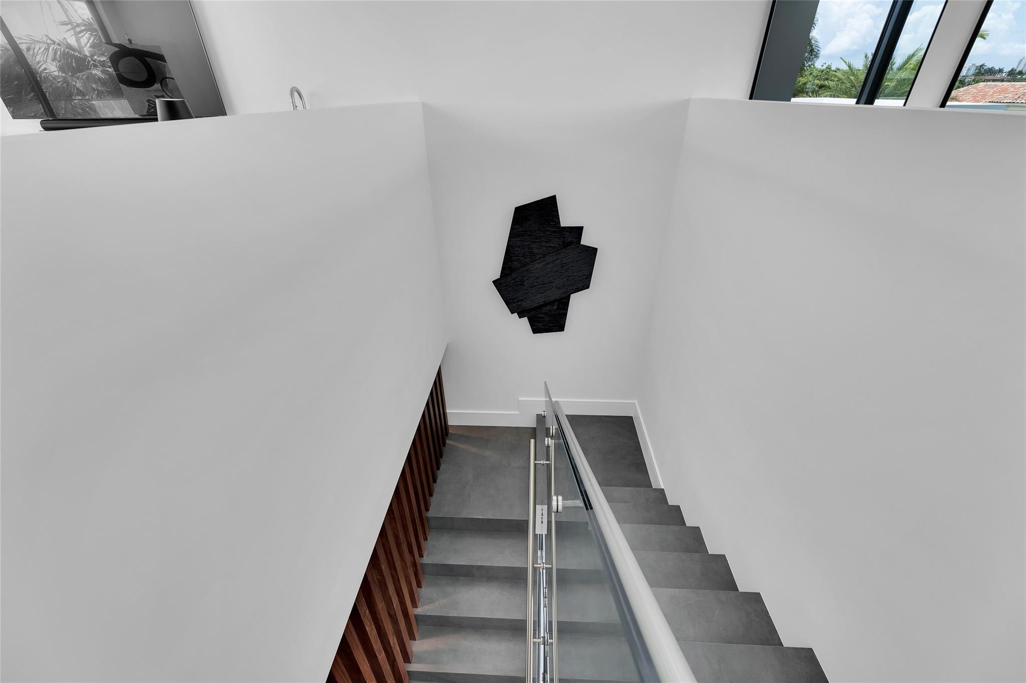 Modern staircase with gray tile steps, glass railing, and dark wood slat detail.