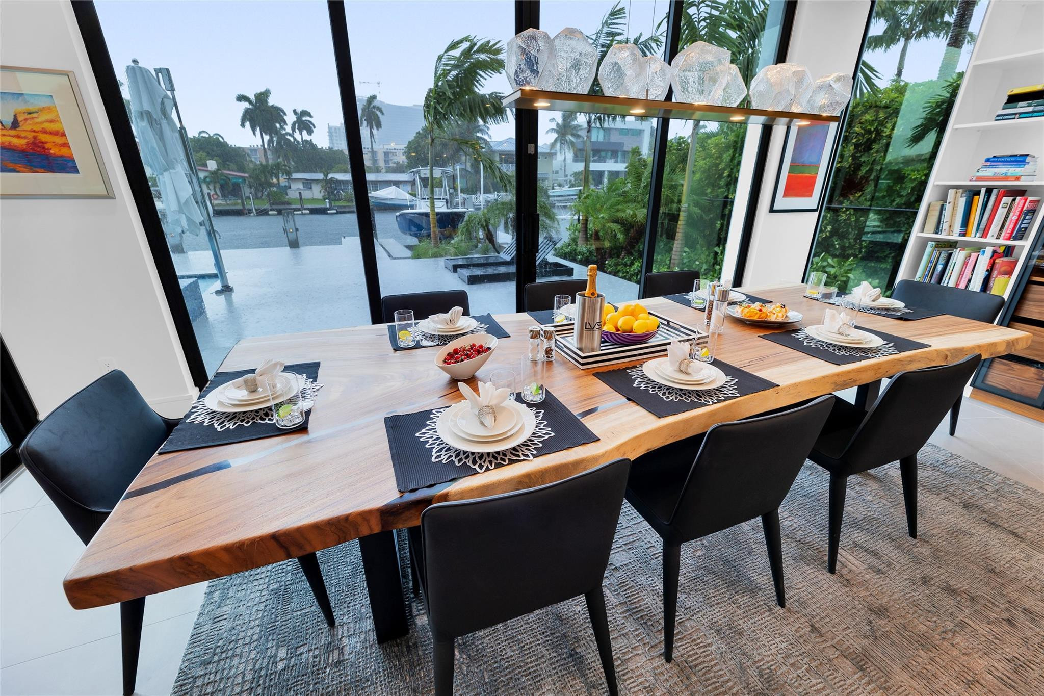 Dining room with a live-edge wood table and canal views through floor-to-ceiling windows.