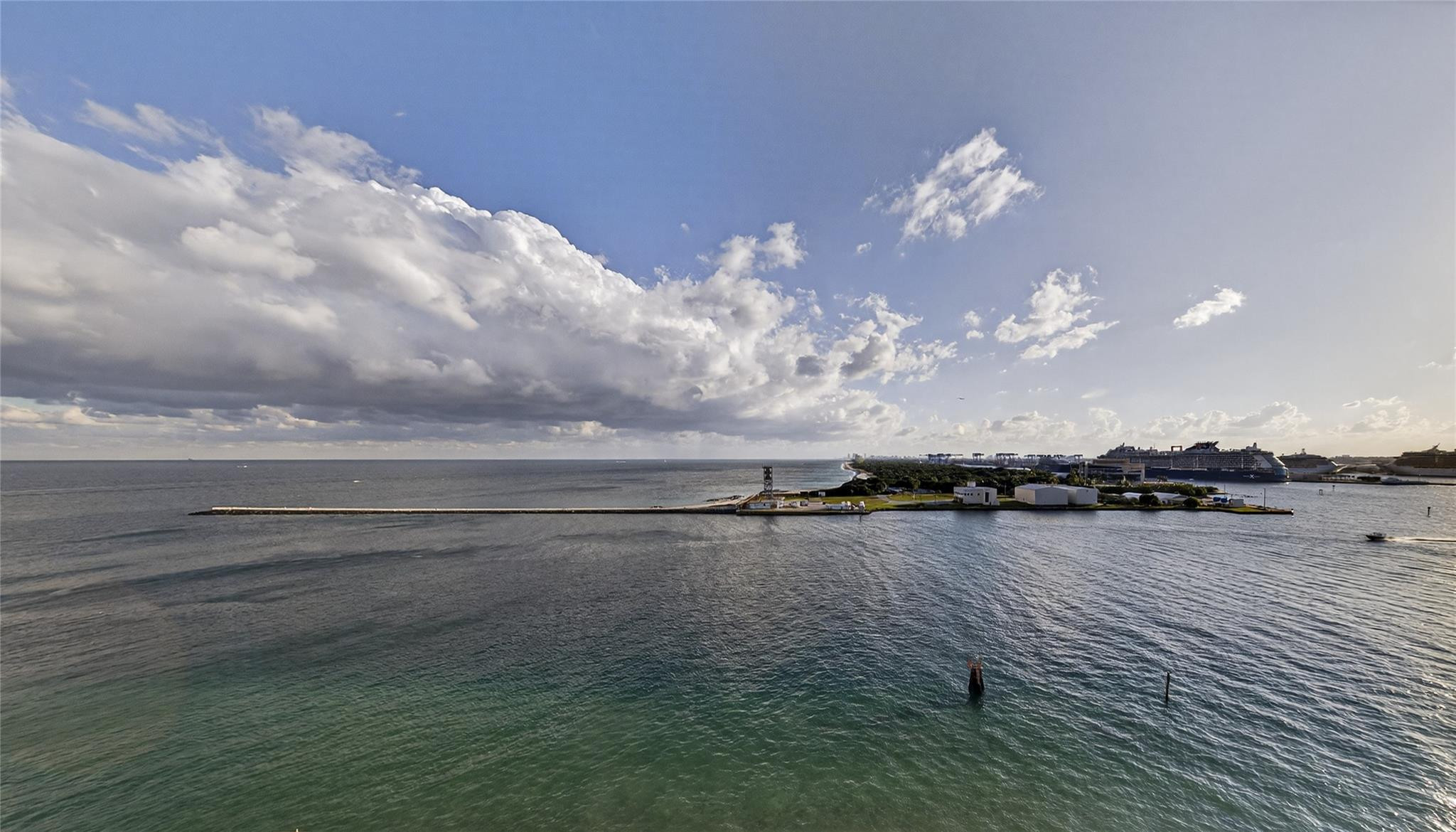 Waterfront view toward a cruise ship terminal and large ships beneath dramatic clouds.