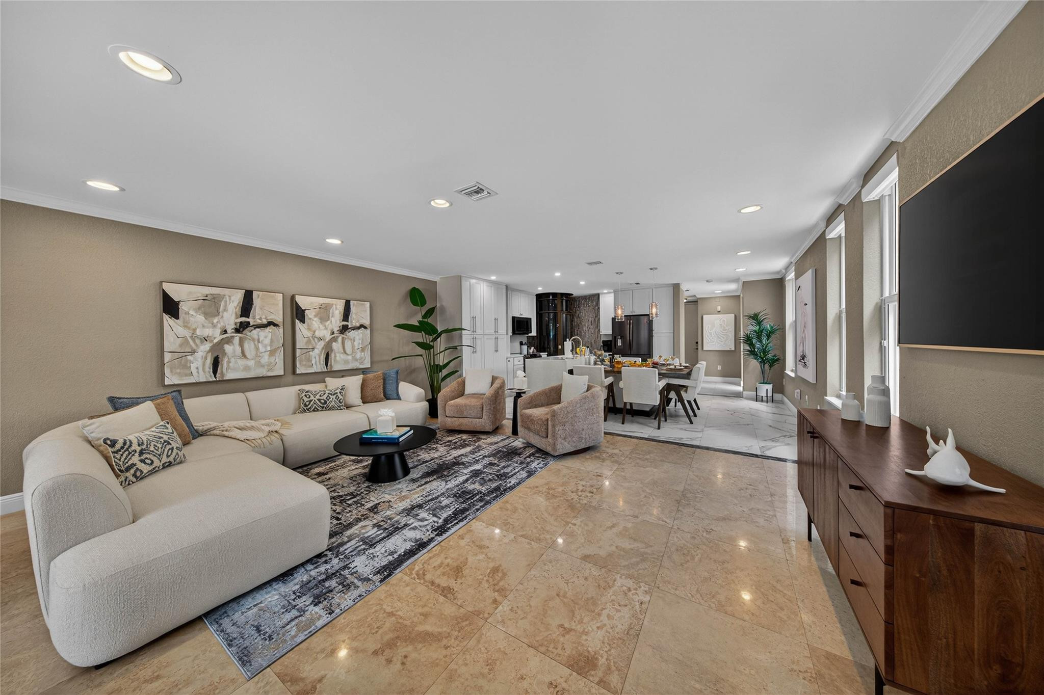 Open-plan living room with cream sectional and patterned rug, dining area and kitchen beyond.
