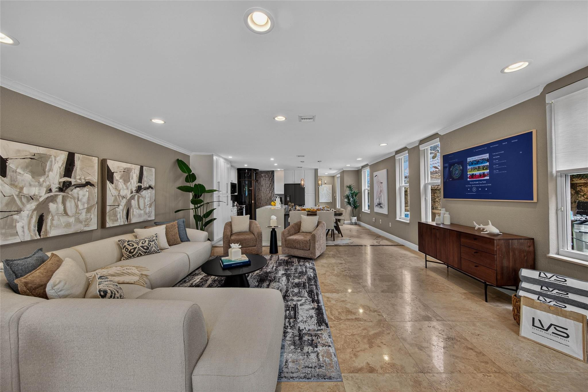 Open-plan living room with a cream sectional, patterned rug, and dining area beside the kitchen.