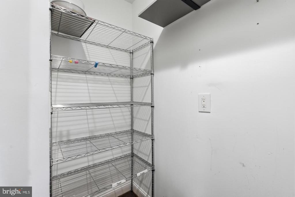 Storage closet with tall chrome wire shelving and a wall outlet.