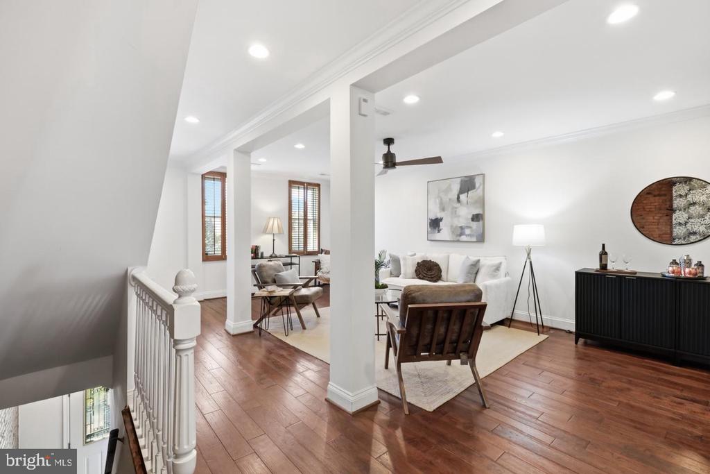 Living room with a white sofa, dark wood floors, and an adjoining dining area.