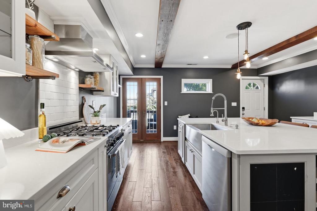 Kitchen with a large white island, stainless steel appliances, and French doors opening to a balcony.