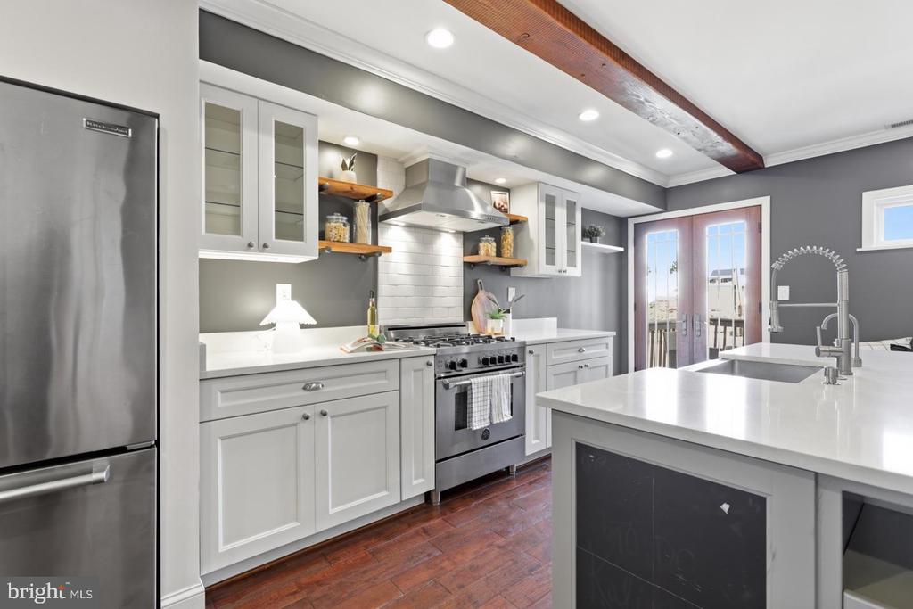 Kitchen with white cabinetry, stainless steel range, large island, and glass doors to a balcony.