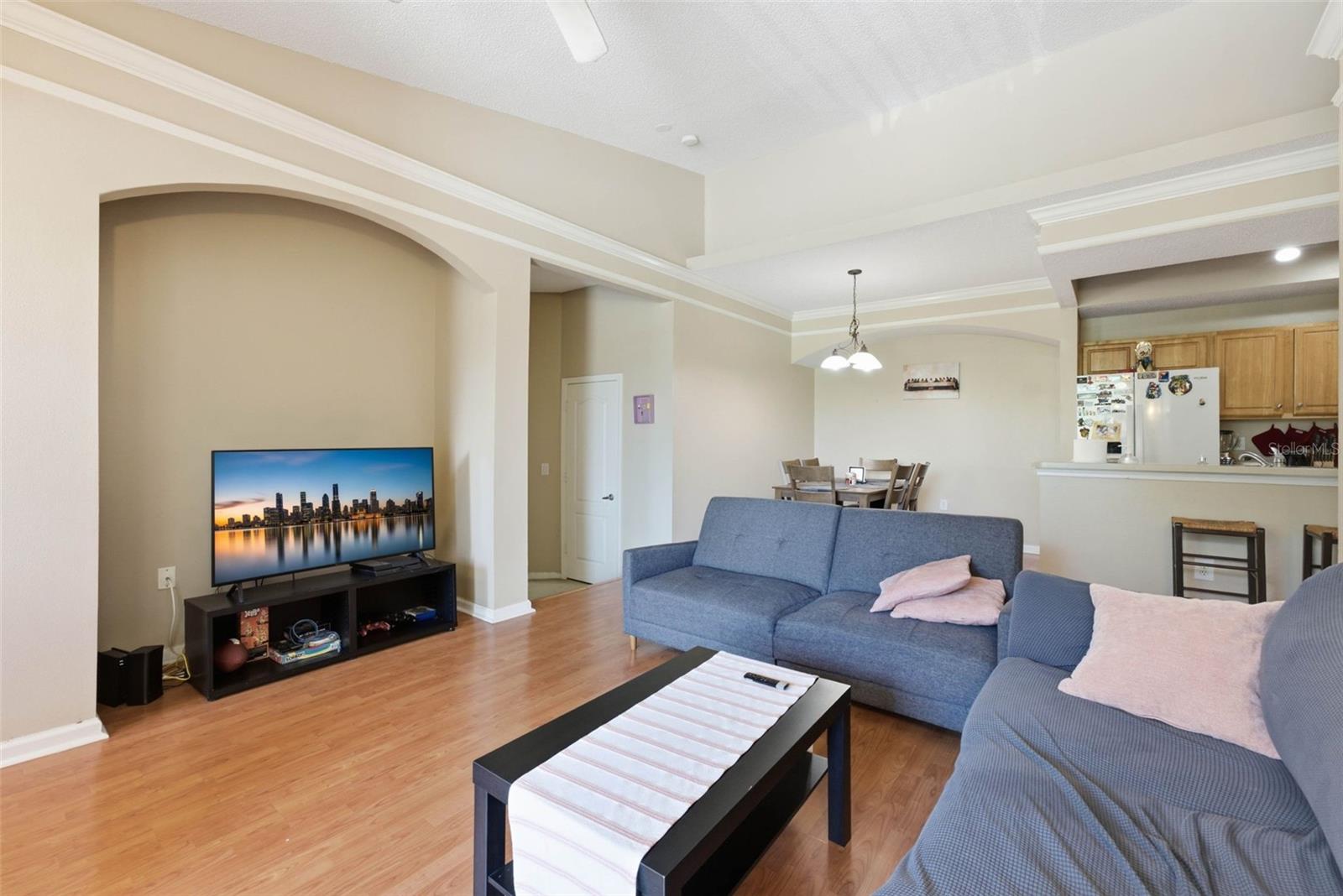 Furnished living room with blue sofas, a black coffee table, and an arched wall opening.