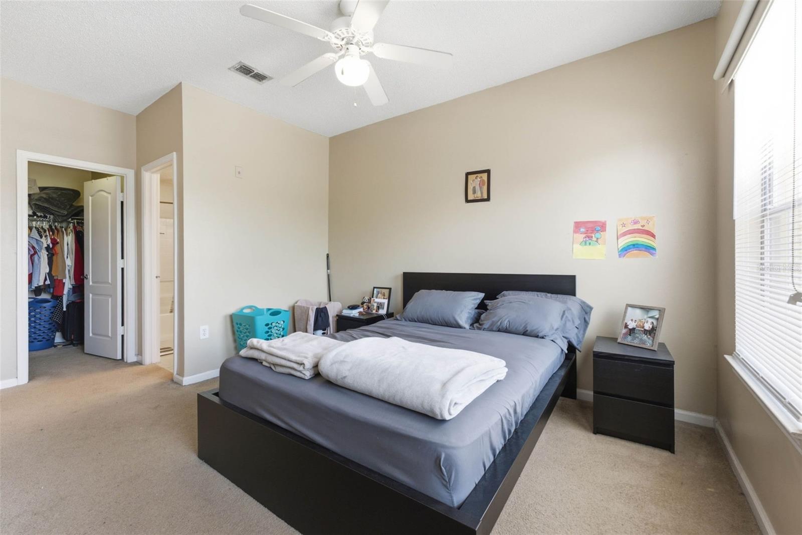 Bedroom with a black platform bed, gray bedding, and open closet doors.