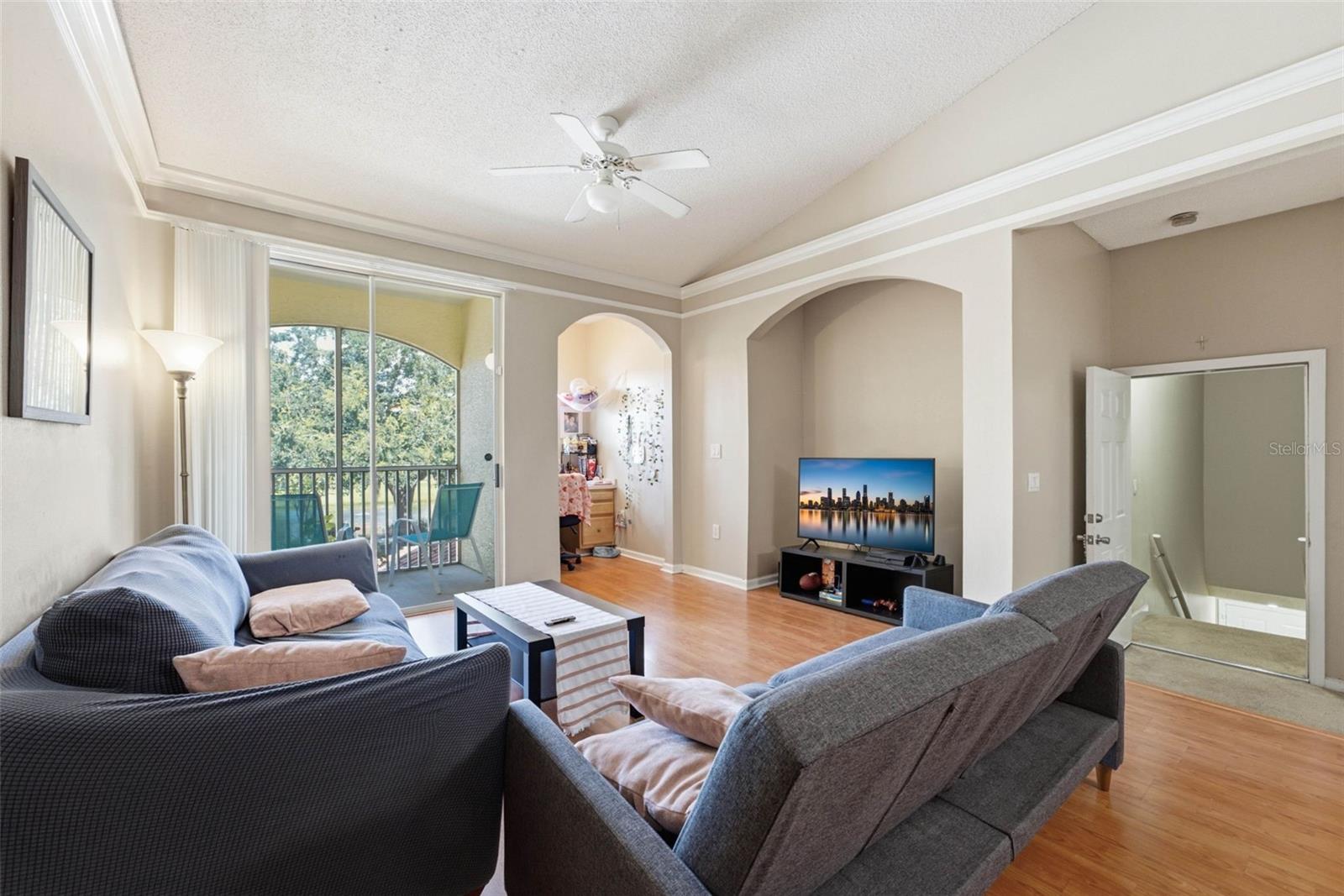 Living room with gray sofas, arched openings, and a sliding glass door to the balcony.