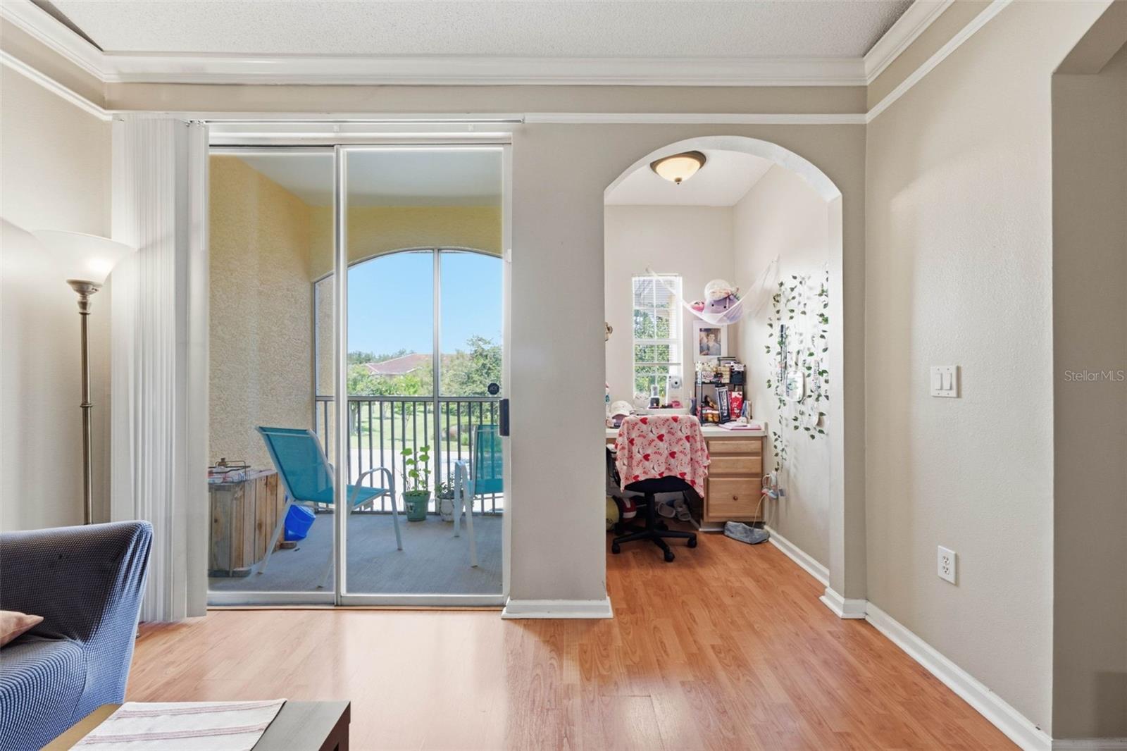 Living room with sliding doors to a balcony and an arched opening to a desk nook.