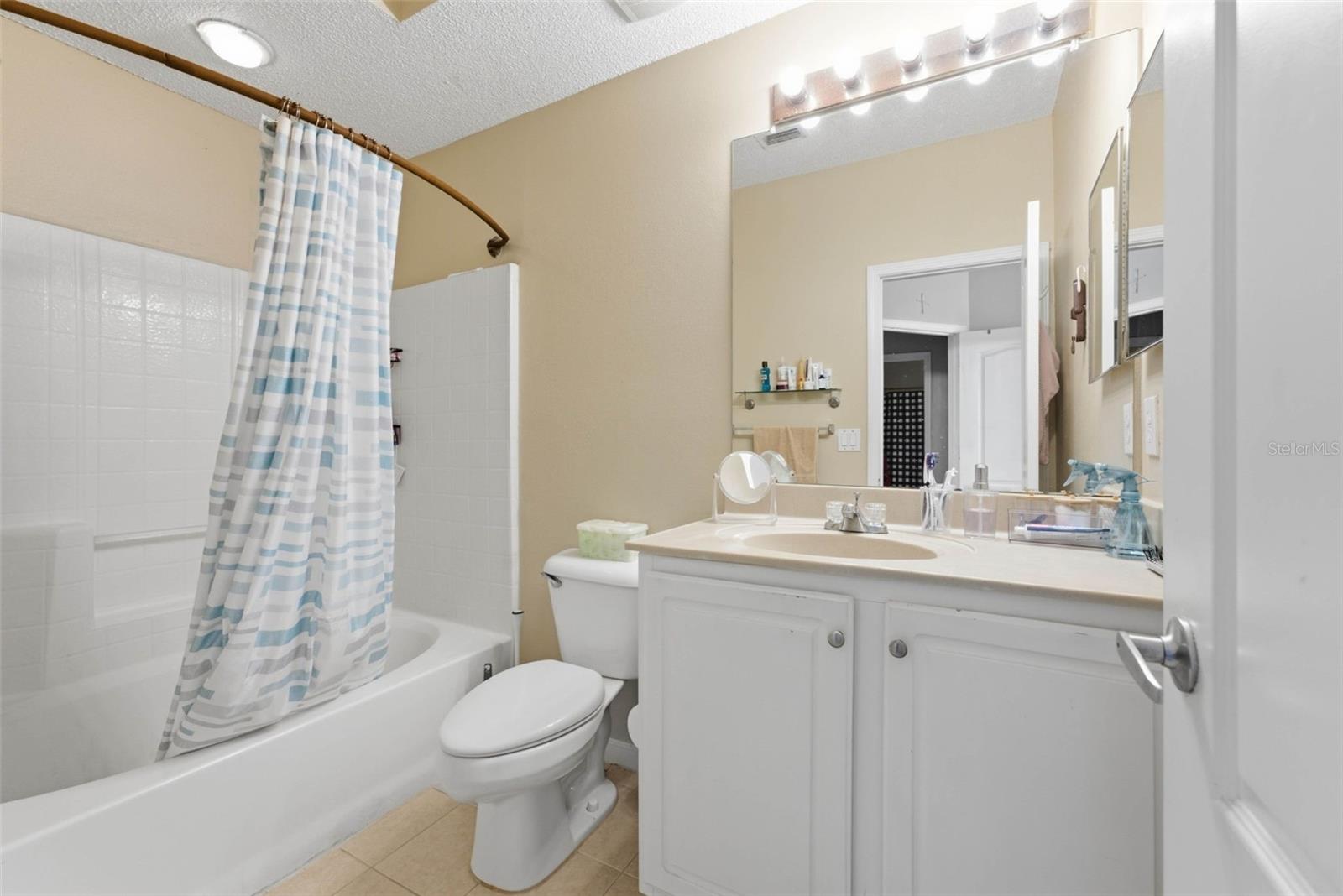 Bathroom with a striped shower curtain, white vanity, and bathtub.