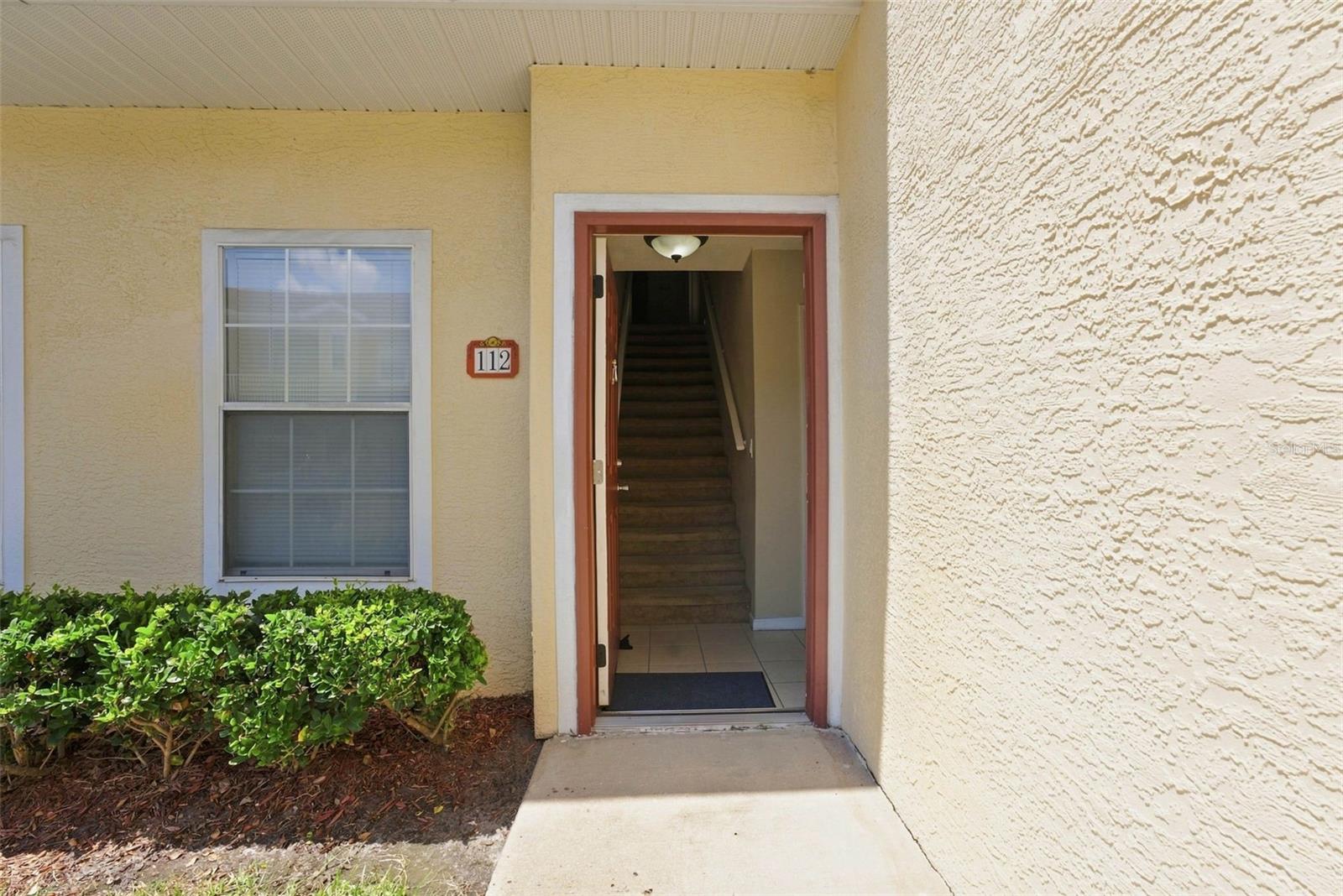 Entrance to unit 112 with an open door revealing an interior staircase.