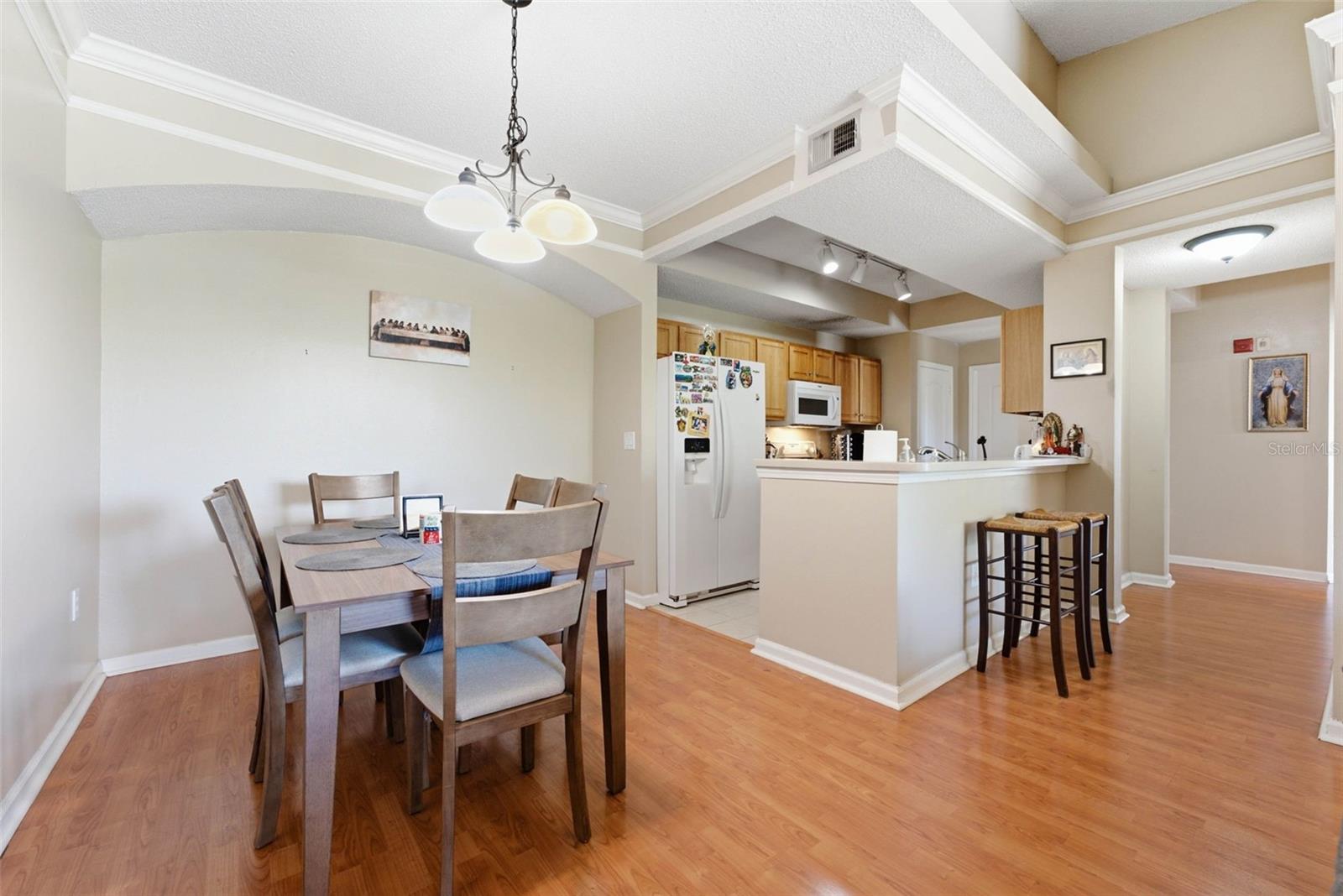 Dining area opening to a kitchen with a breakfast bar and vaulted ceiling.