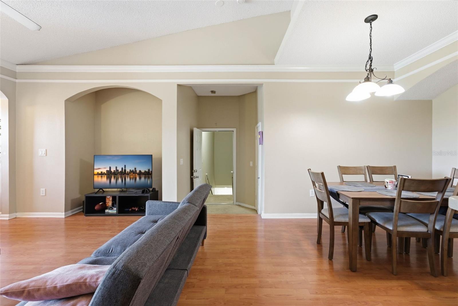 Open living and dining area with a gray sofa, television, and wood dining set.