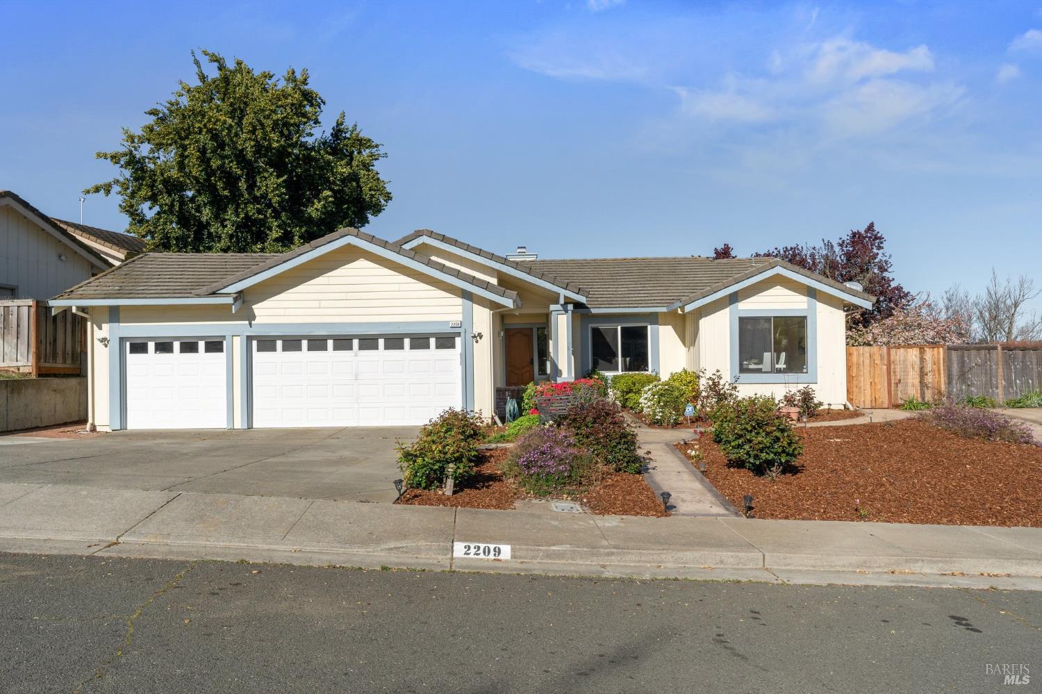 Single-story beige home with a two-car garage and landscaped front yard.