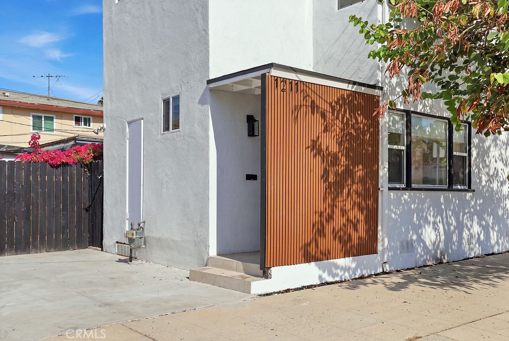 White stucco home with a vertical wood-slat entry screen and broad concrete driveway.