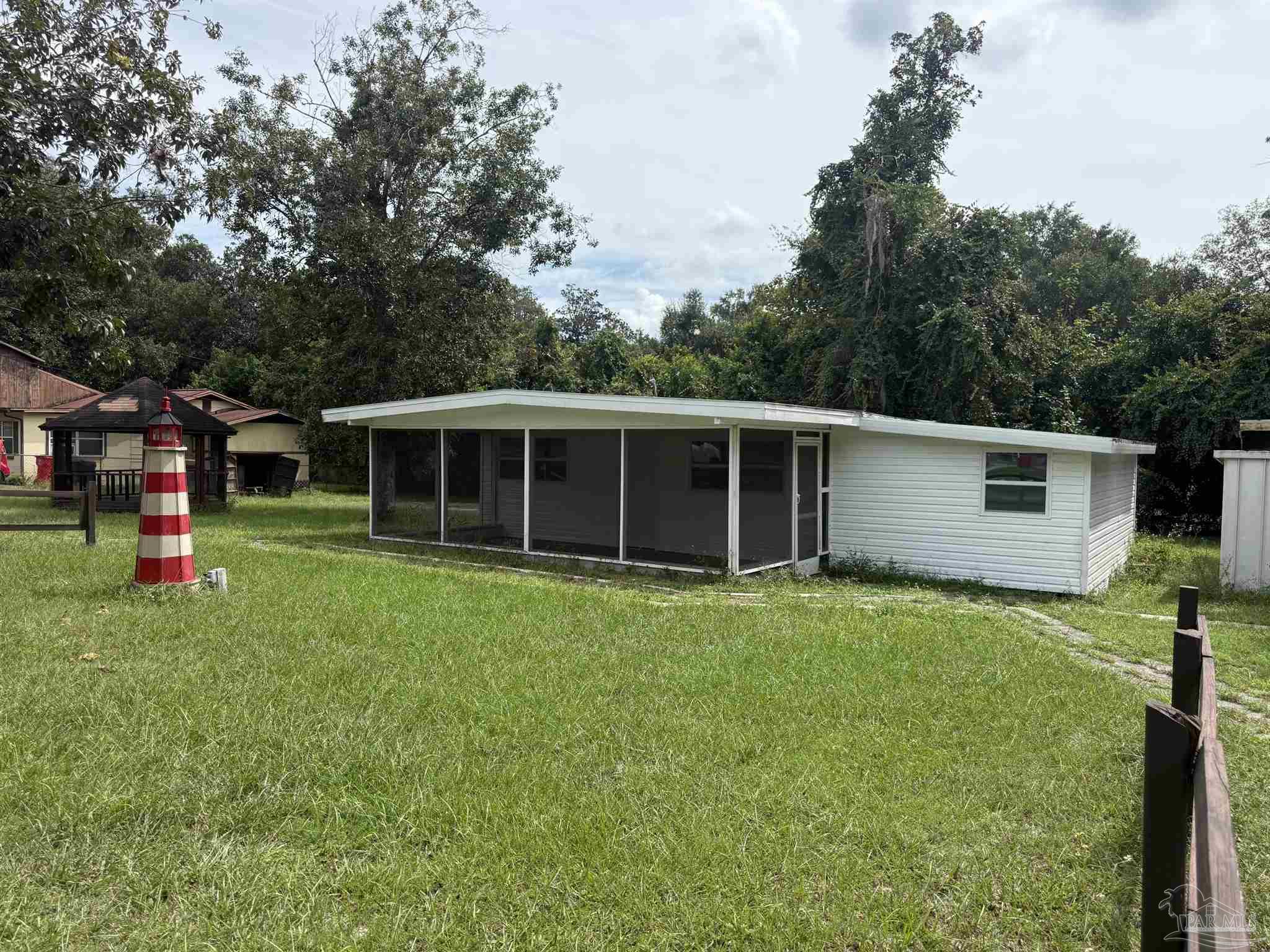 Single-story white home with a long screened porch and grassy lawn