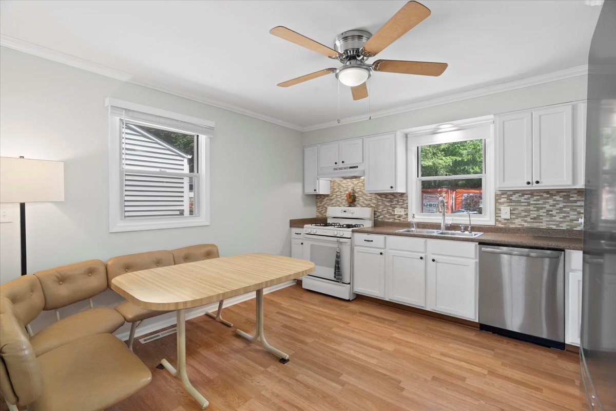 Kitchen with white cabinets, stainless-steel dishwasher, and a tan breakfast nook with table.