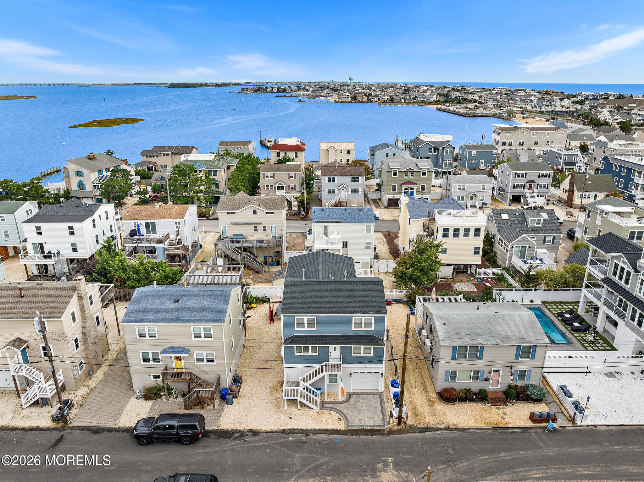Aerial view of coastal homes beside a broad bay, with the ocean on the horizon.