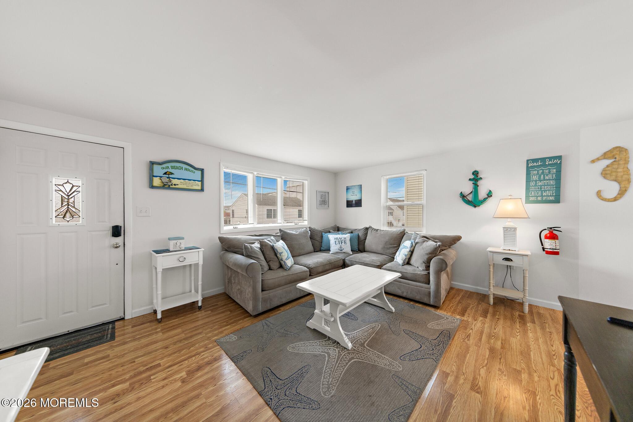 Furnished living room with a gray sectional, white coffee table, and coastal decor.