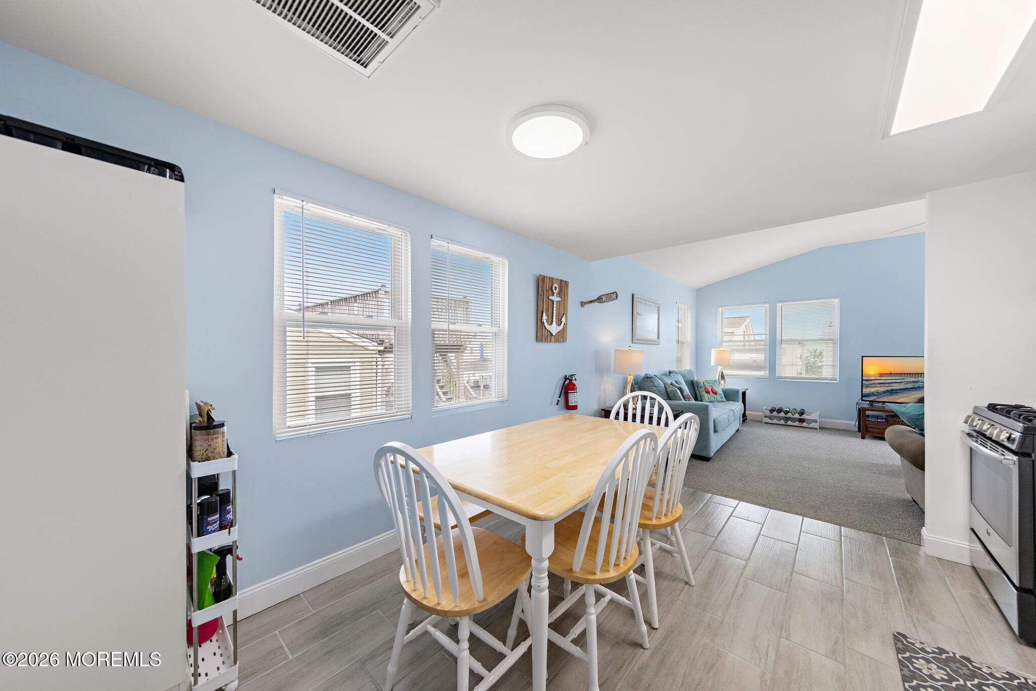 Dining and living area with a light wood table, white chairs, blue walls, and a blue sofa.