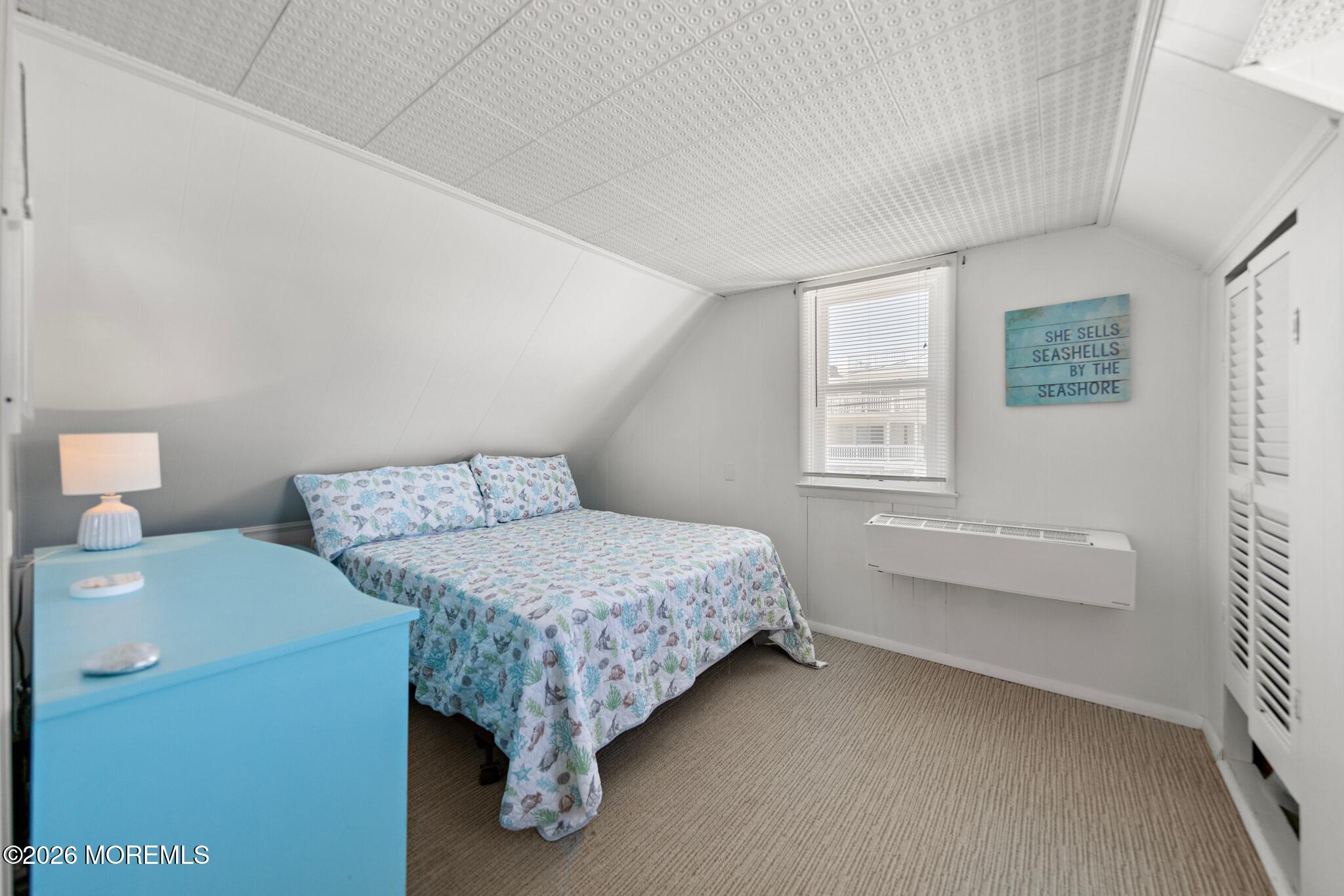 Bedroom with sea-life print bedding, turquoise dresser, and sloped ceiling.