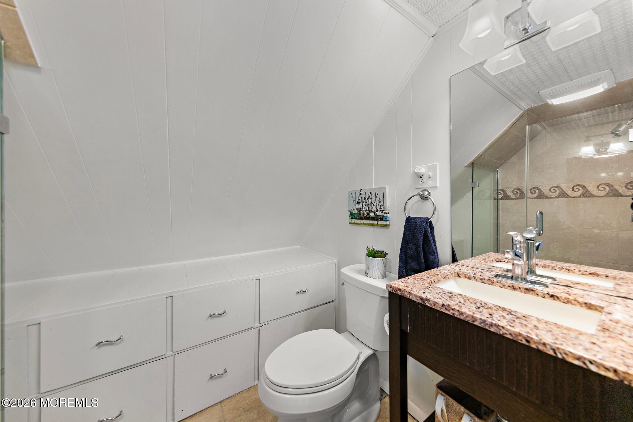 Bathroom with built-in white drawers, a granite vanity, and a glass-enclosed tiled shower.