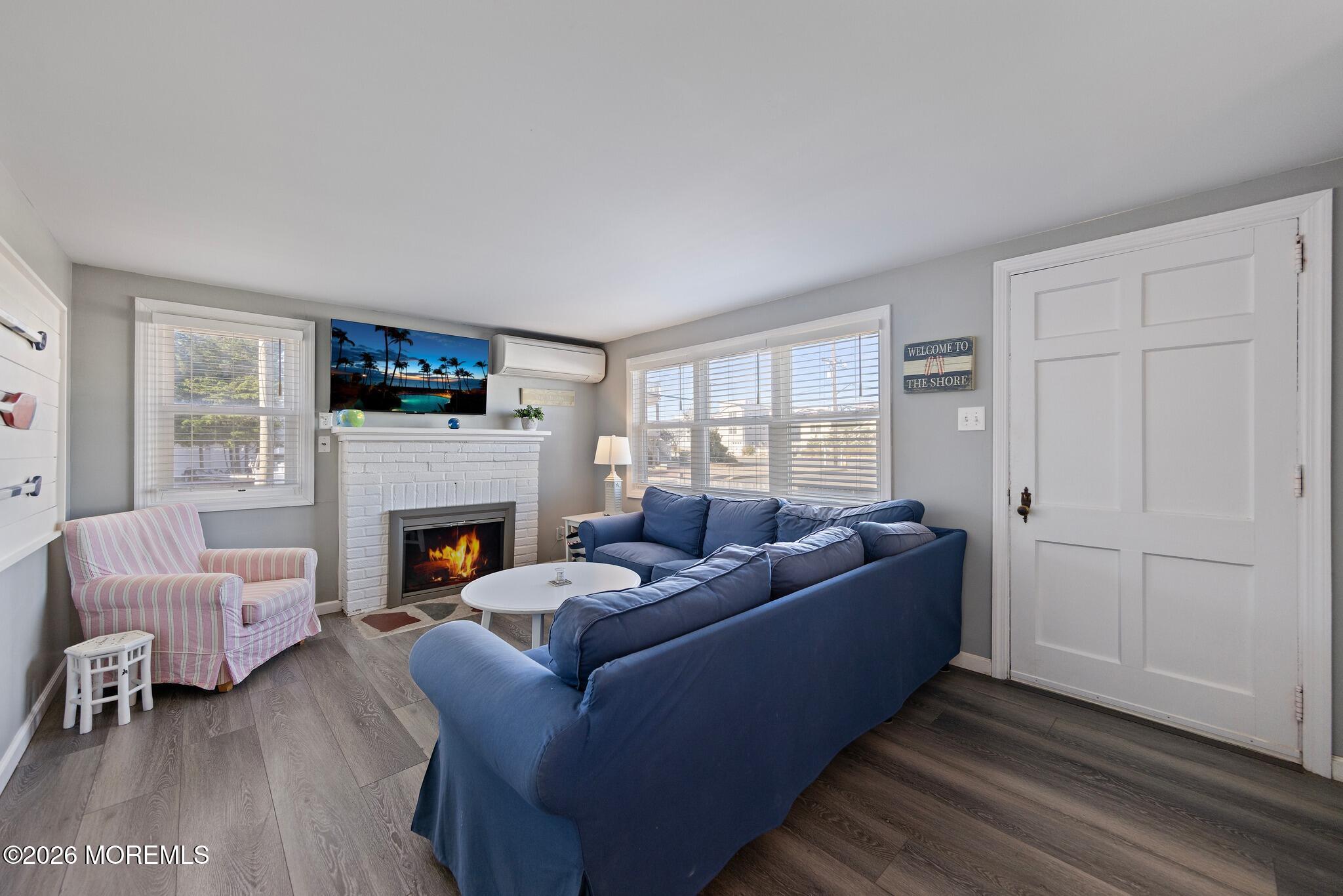 Living room with a blue sectional, white brick fireplace, and wide windows.