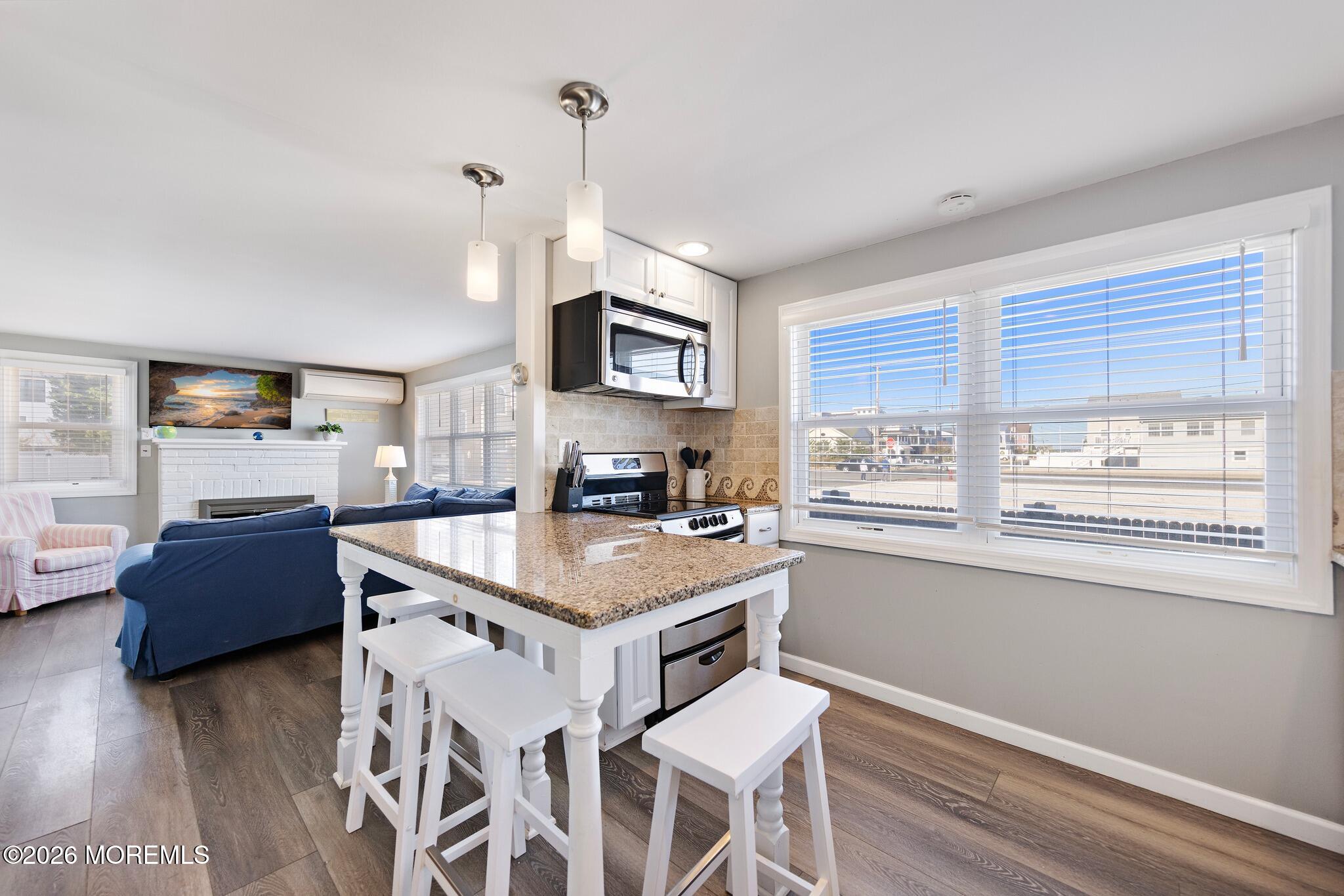 Open-plan kitchen and living area with a granite island, stainless appliances, and blue sofa.