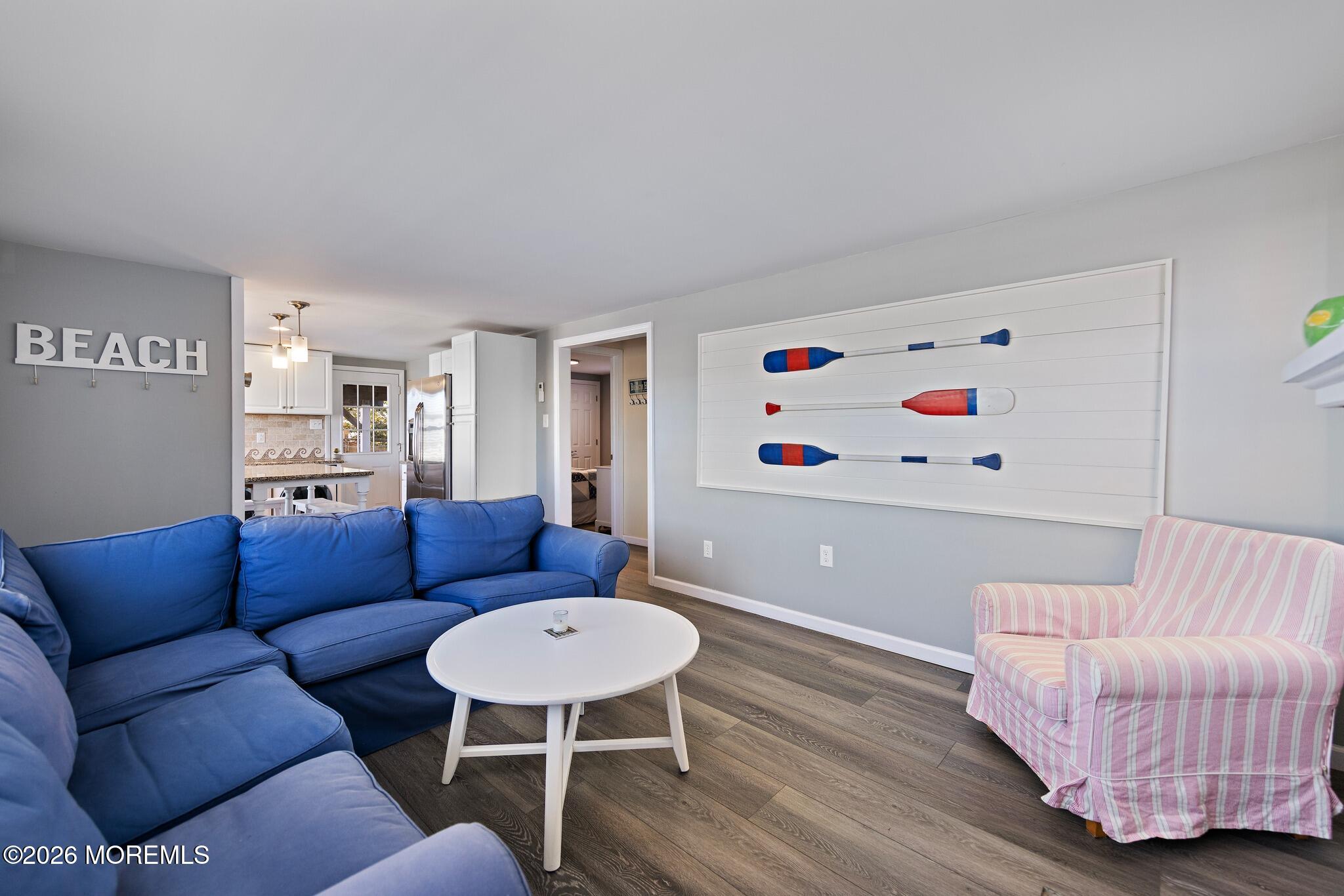 Living room with a blue sectional, pink striped armchair, and decorative oars on the wall.