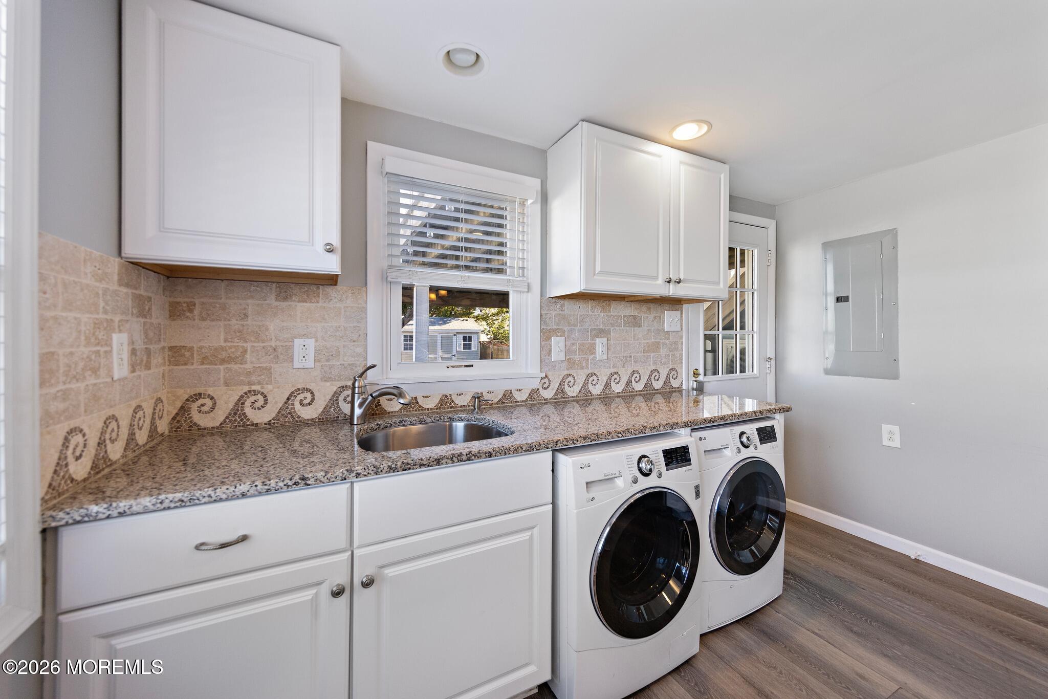 Laundry room with front-loading washer and dryer, granite counter, and decorative tile backsplash.