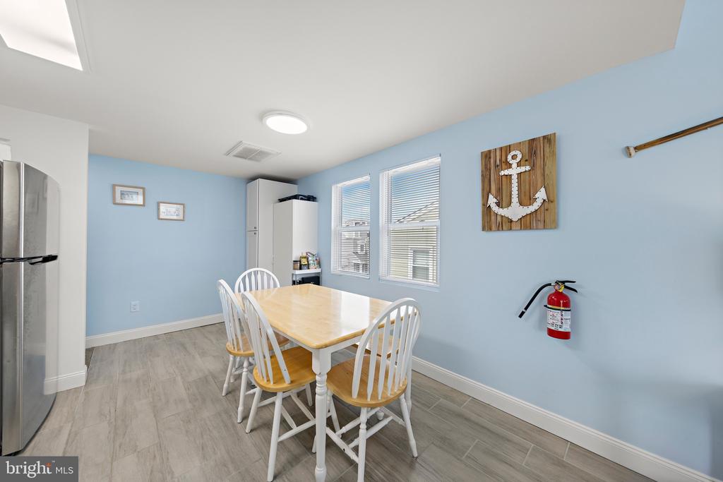 Dining area with a light wood table, white chairs, blue walls, and a wooden anchor decoration.