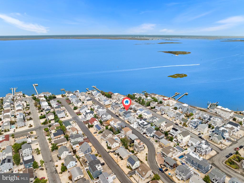 Aerial view of coastal homes along the bay, with a location marker over one house.