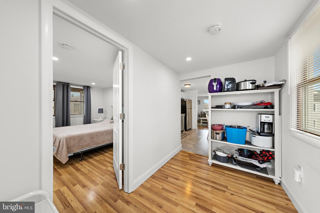 Interior storage area with open shelving, small appliances, and a view into a bedroom.