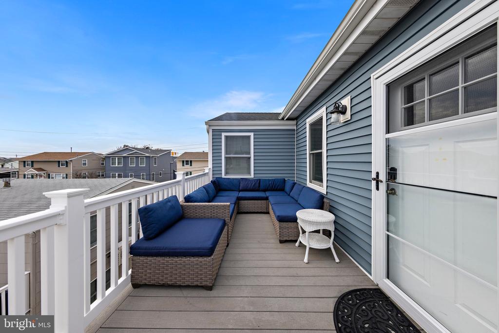 Rooftop deck with blue sectional seating, gray decking, and white railing.