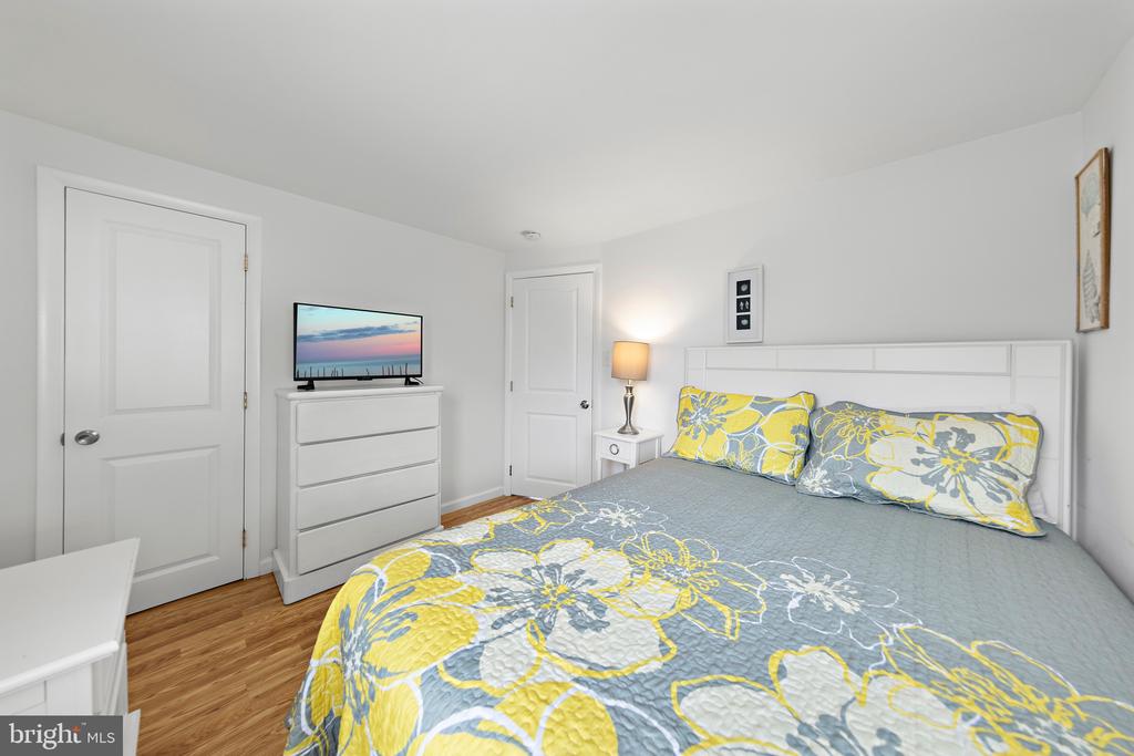 Bedroom with gray and yellow floral bedding, a white dresser, and wood flooring.