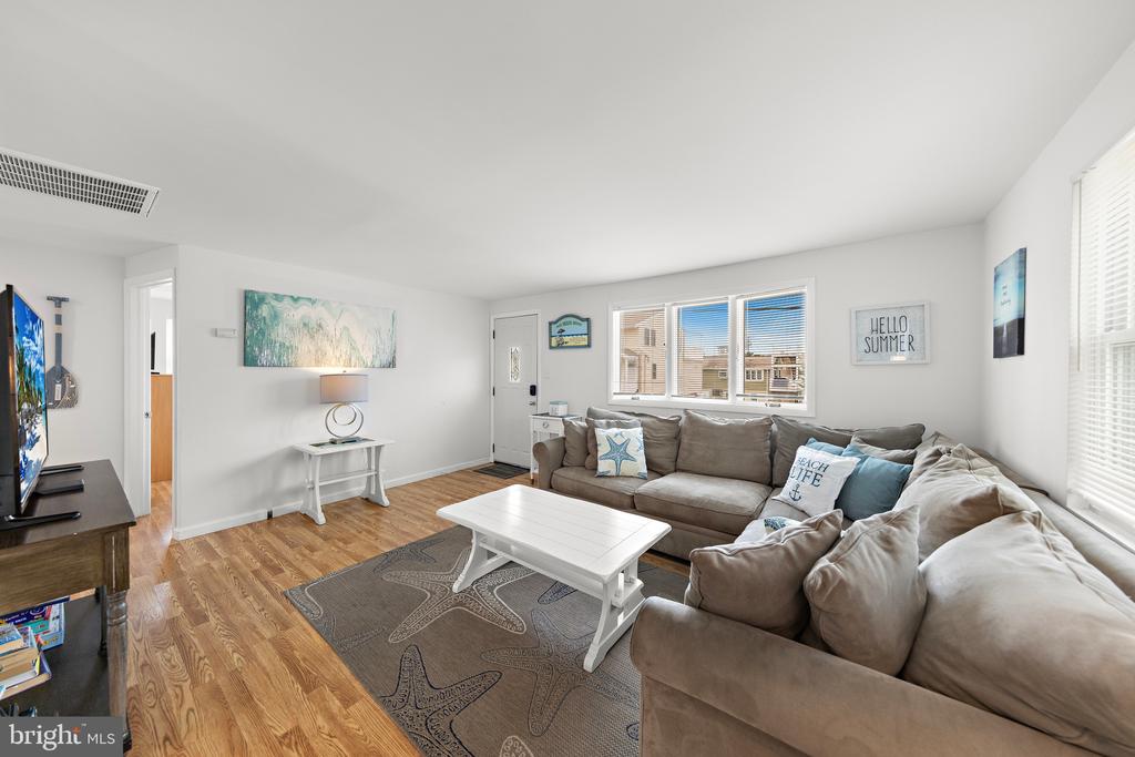 Living room with a beige sectional, white coffee table, starfish-patterned rug, and hardwood floors.