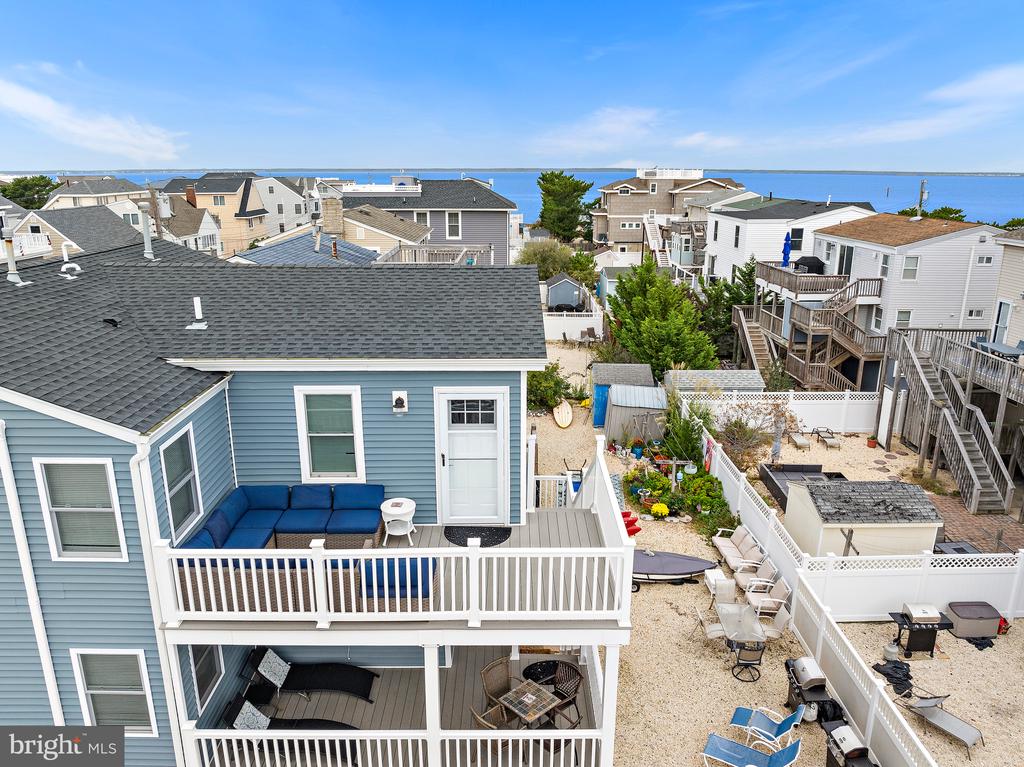 Blue coastal home with a spacious deck and sandy yard overlooking the bay.
