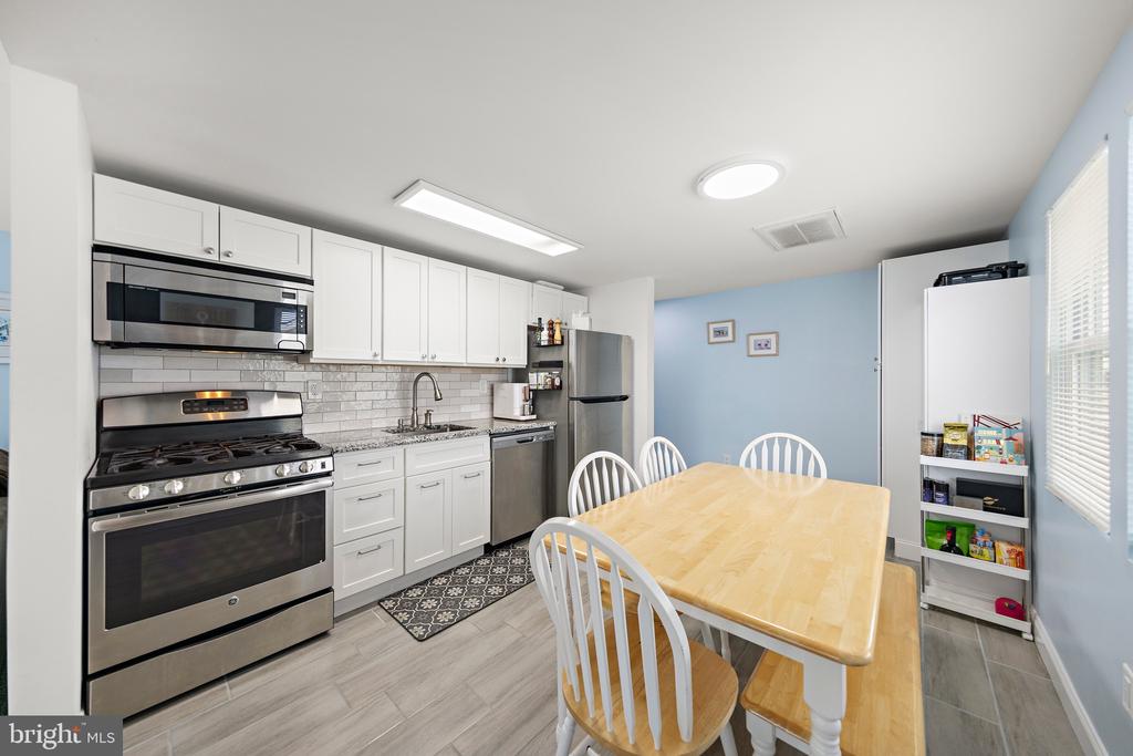 Kitchen and dining area with white cabinetry, stainless steel appliances, and a light wood table.