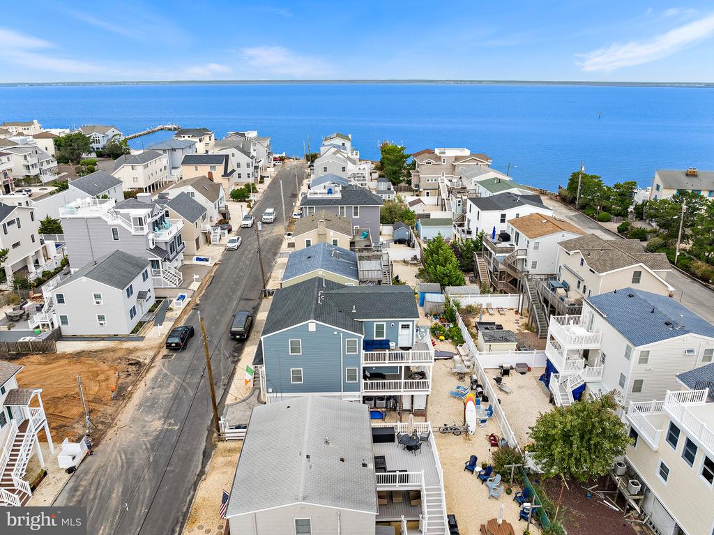 Aerial view of beachside homes along a road beside blue water.