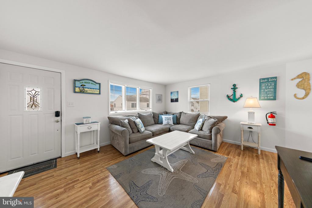 Living room with a gray sectional, white coffee table, patterned rug, and beach-themed decor.