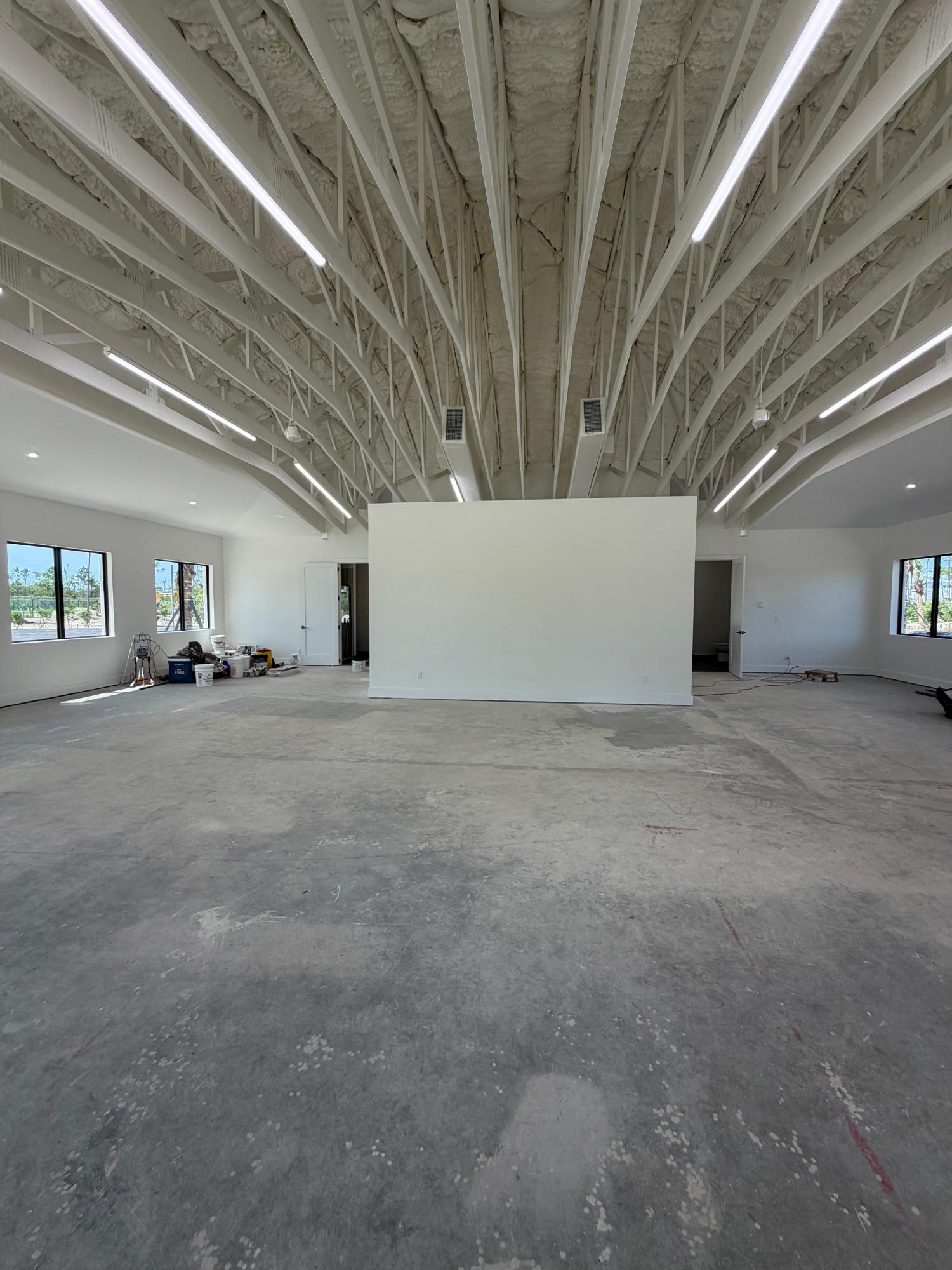 Unfinished open interior with a high exposed-beam ceiling and bare concrete floor.