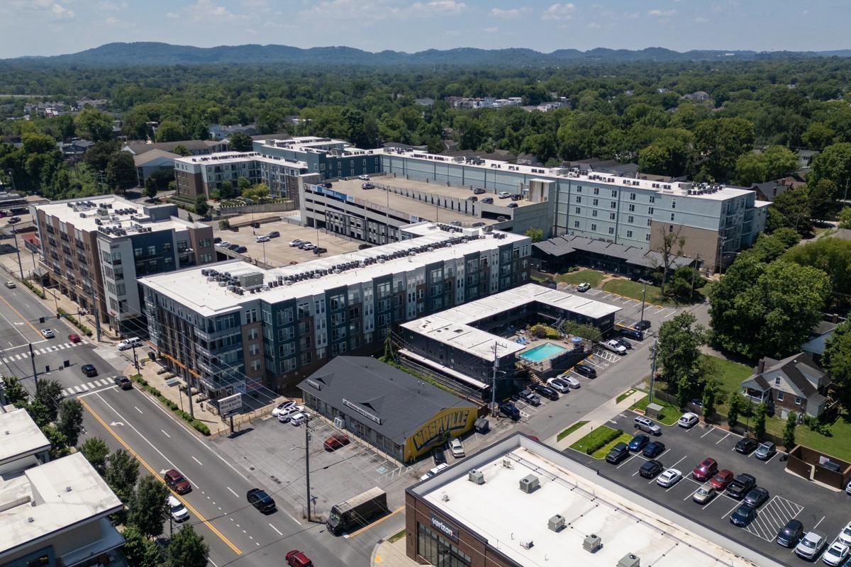 Aerial view of a Nashville apartment complex with a courtyard pool and wooded hills beyond.
