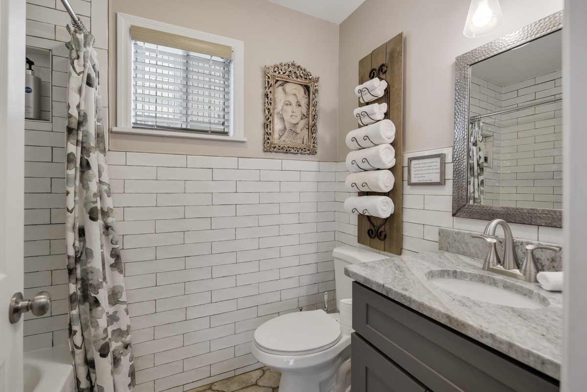 Bathroom with white subway tile, a floral shower curtain, and a gray marble-top vanity.