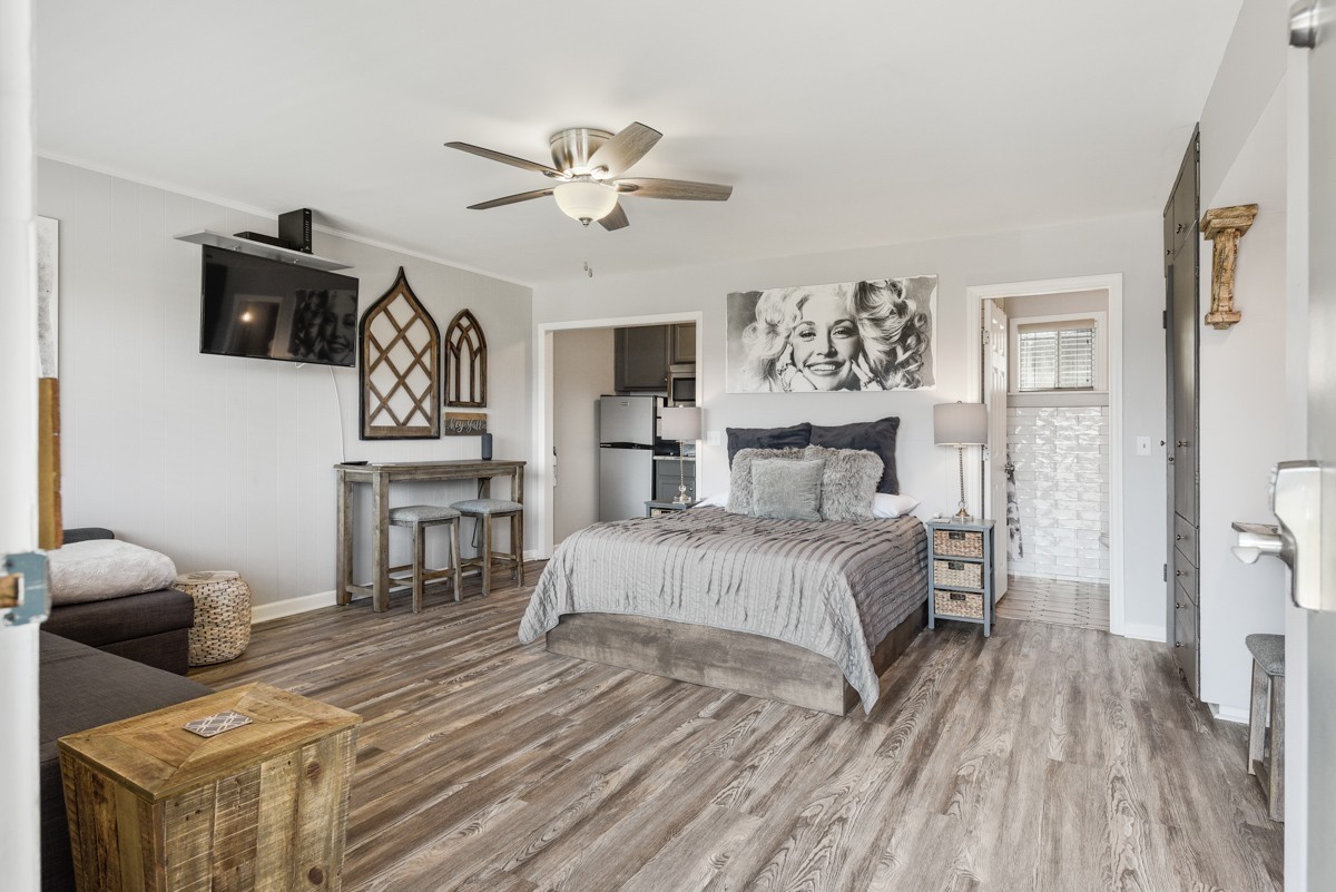 Furnished bedroom with a gray bed, ceiling fan, and wood-look flooring.