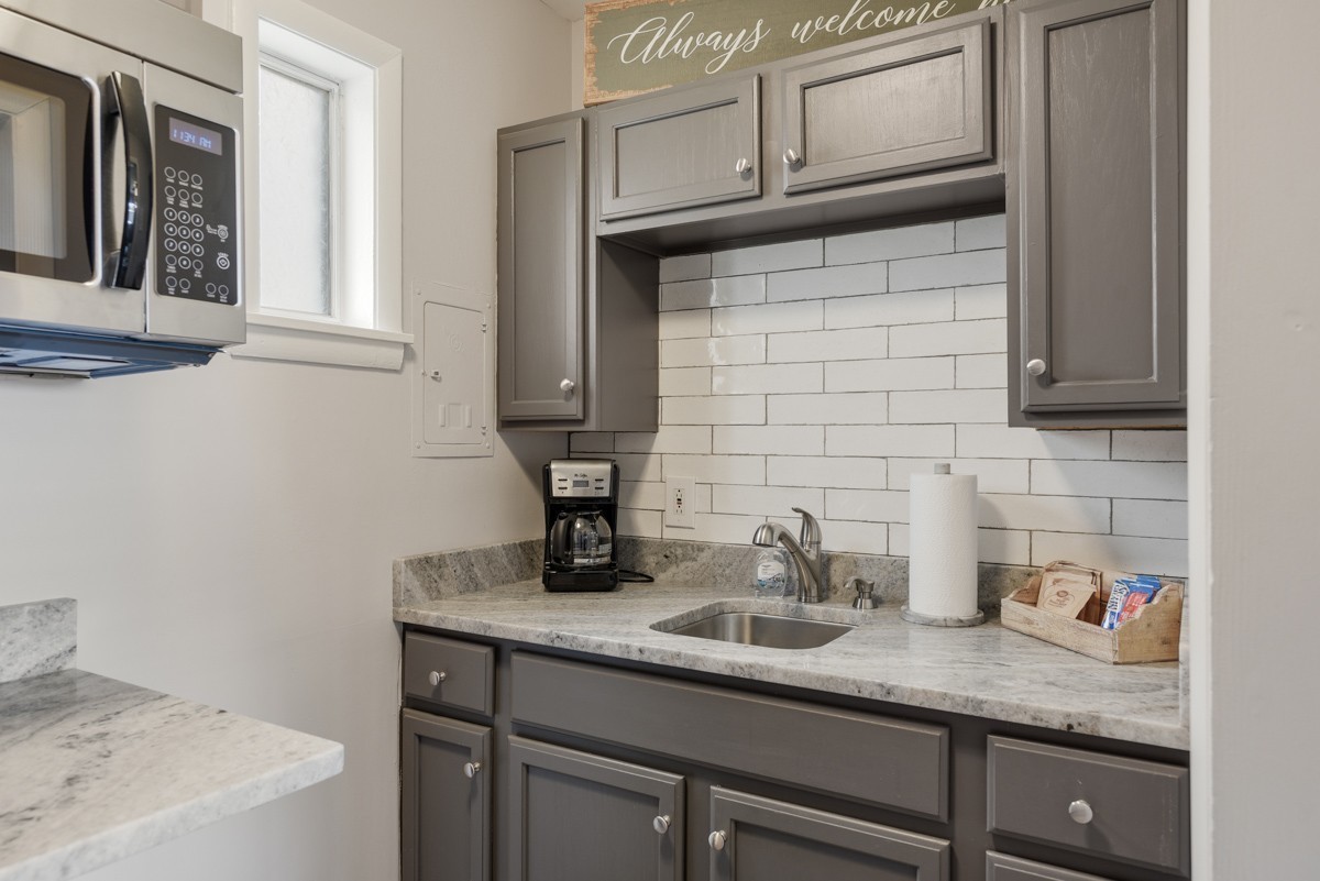 Kitchen with gray cabinets, white subway tile backsplash, and a marble-pattern countertop.