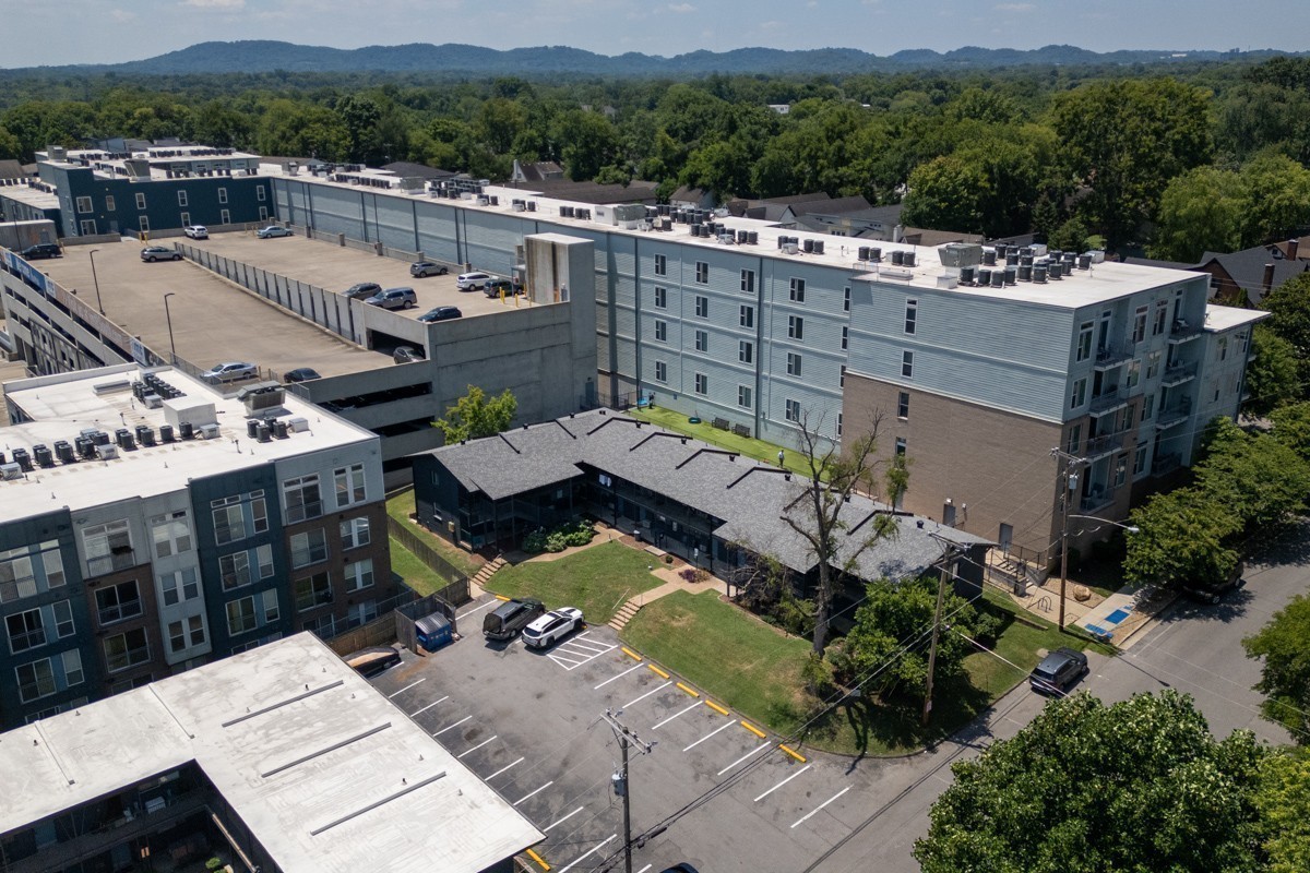 Aerial view of an apartment complex with rooftop parking and a landscaped courtyard.